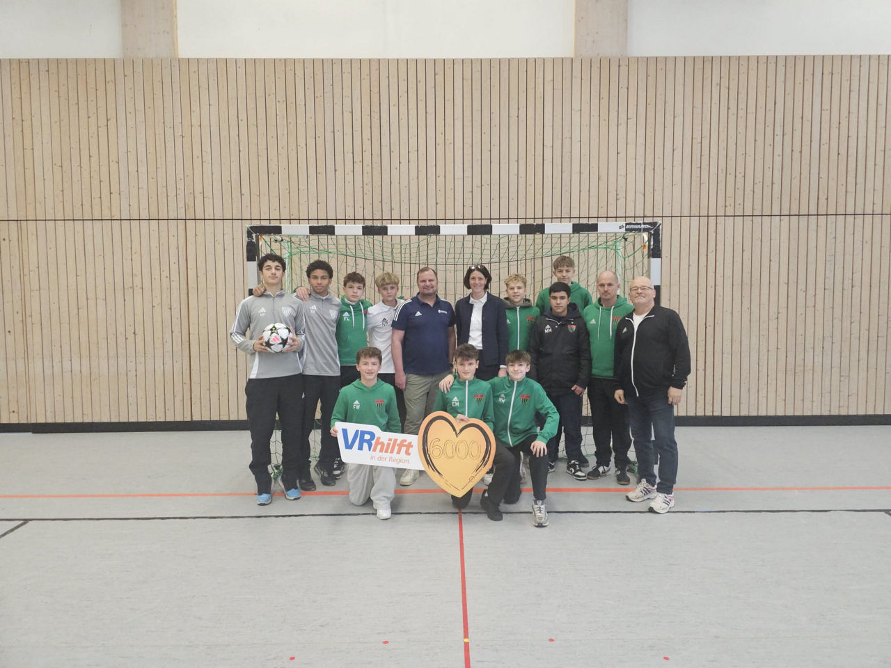 Auf dem Foto ist die U15-Mannschaft des 1. FC Schweinfurt 05 zu sehen. Sie erhalten von einer Frau einen Spendenscheck in Höh
