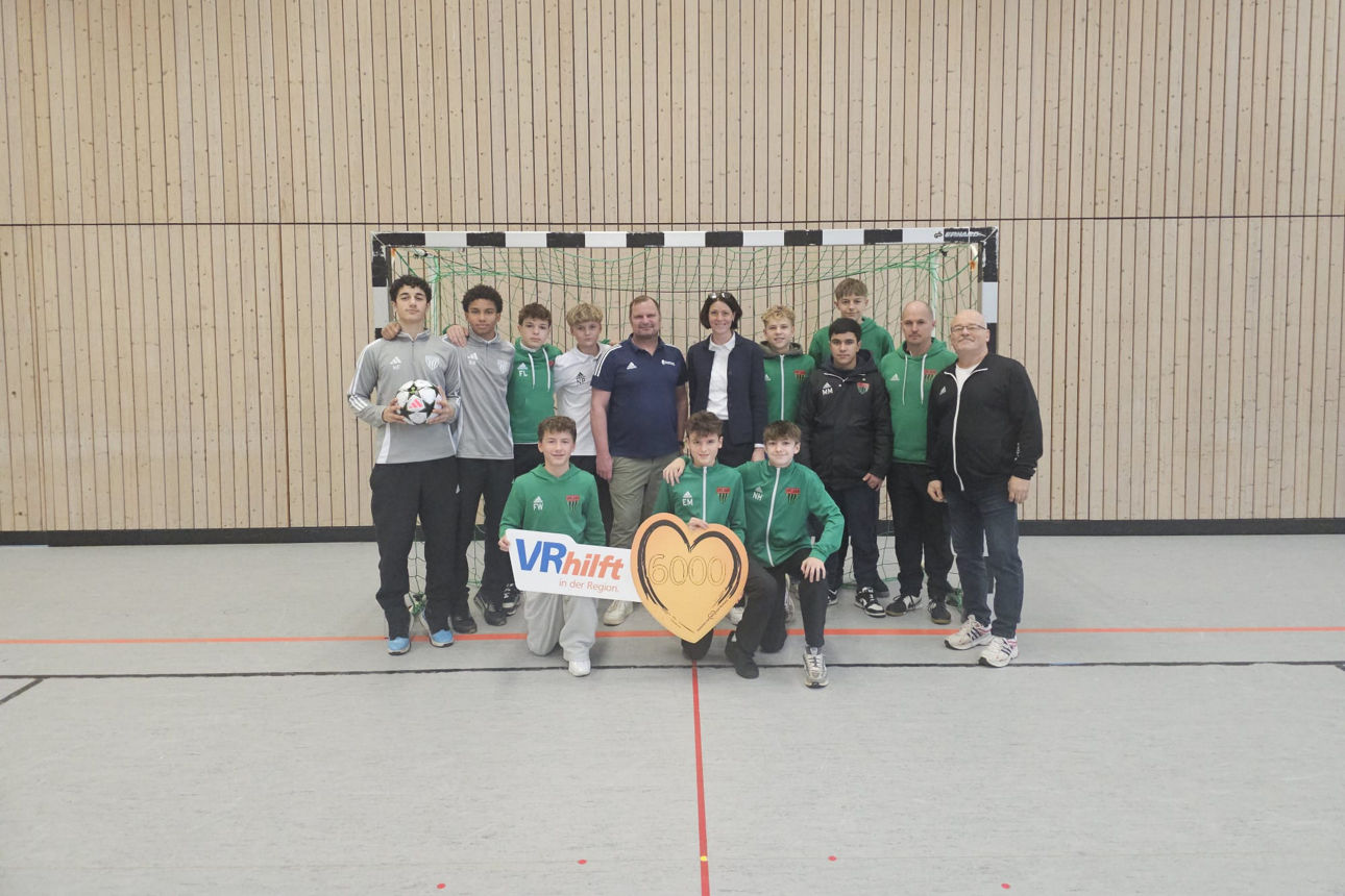 Auf dem Foto ist die U15-Mannschaft des 1. FC Schweinfurt 05 zu sehen. Sie erhalten von einer Frau einen Spendenscheck in Höh