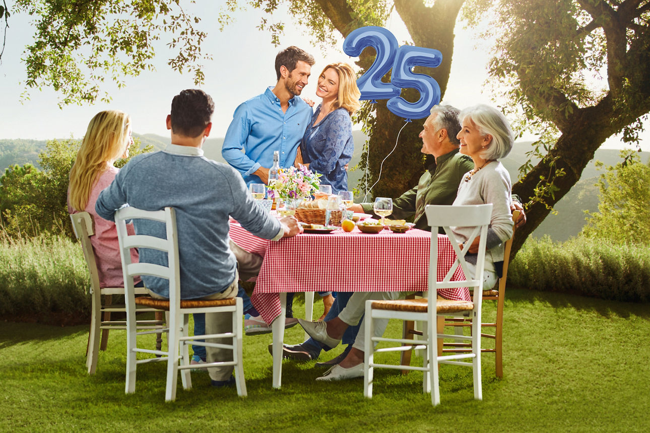 Familie sitzt auf einer Wiese am Tisch