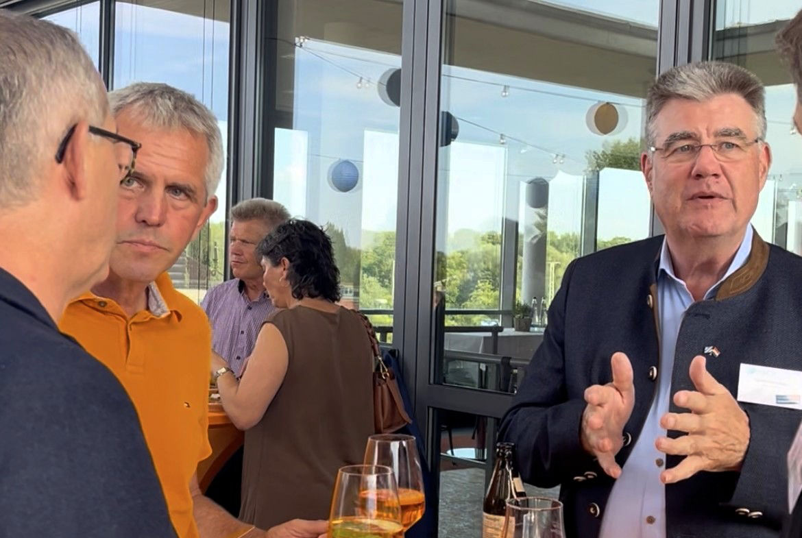 Drei Männer stehen diskutierend vor einer Glasfront 