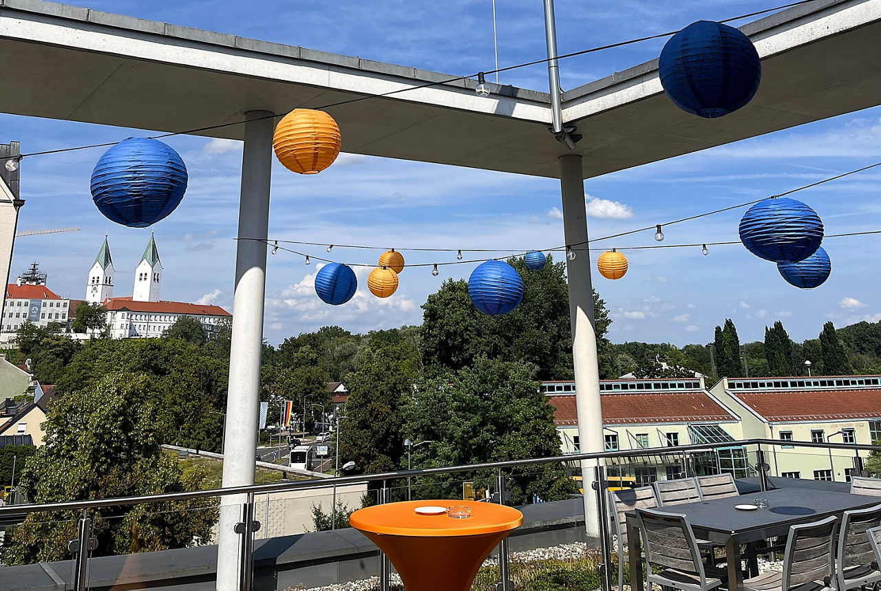 Für den Unternehmertag mit blauen und orangenen Lampions geschmückte Dachterrasse mit Blick auf den Freisinger Domberg