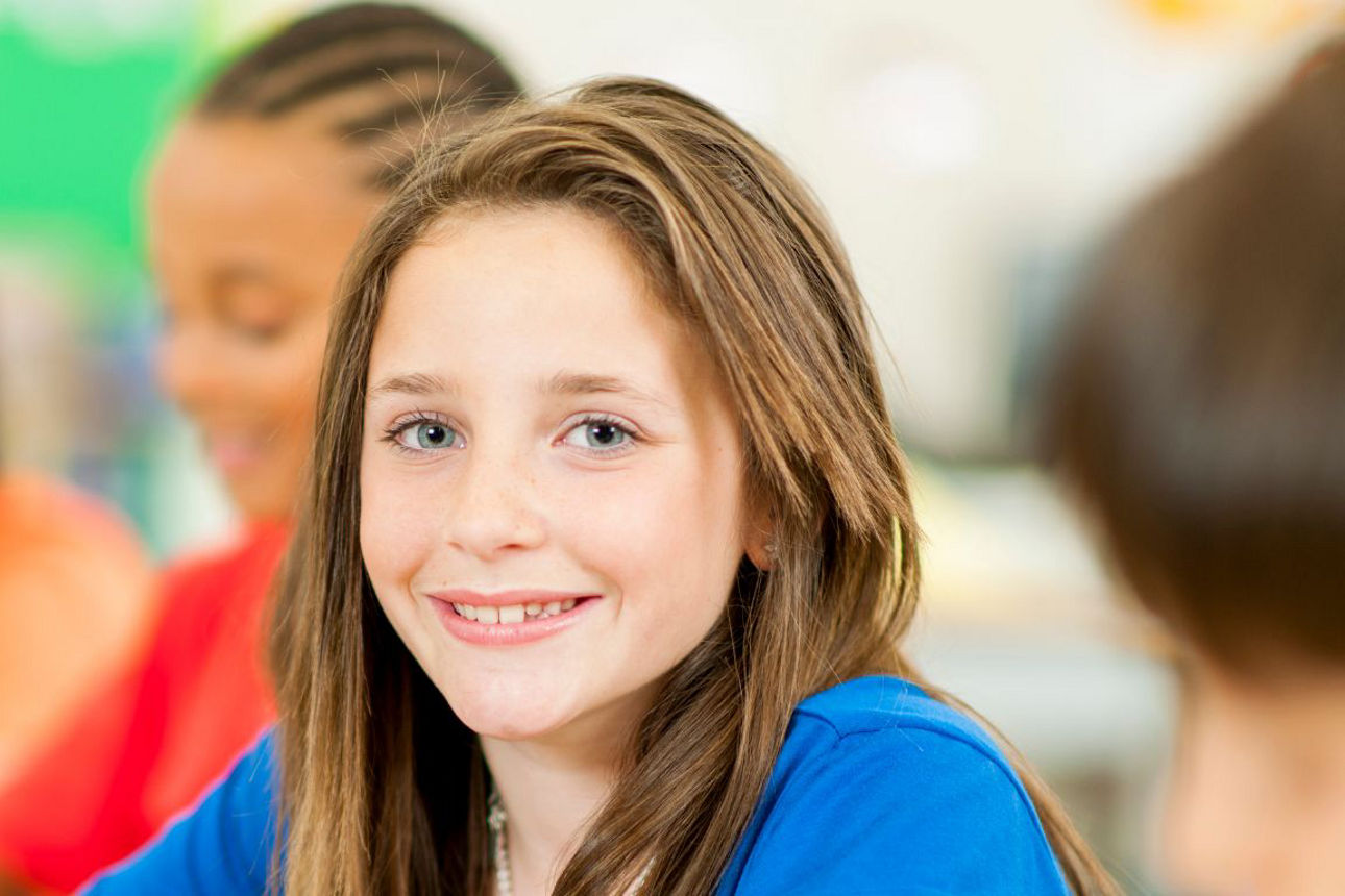 Junges Mächen sitzt im Klassenzimmer.