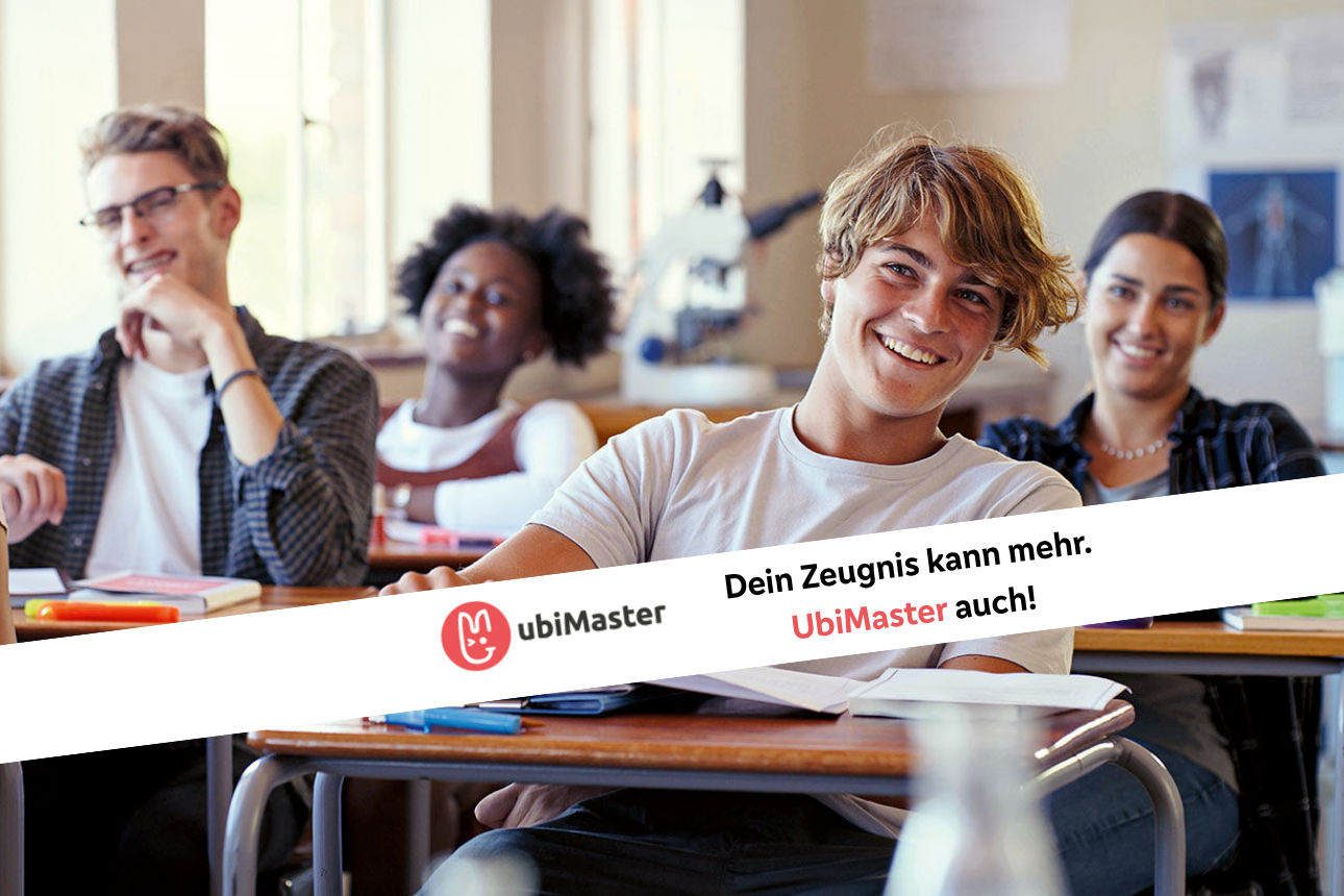 Schülerinnen und Schüler sitzen in einem Klassenraum und lächeln in die Kamera