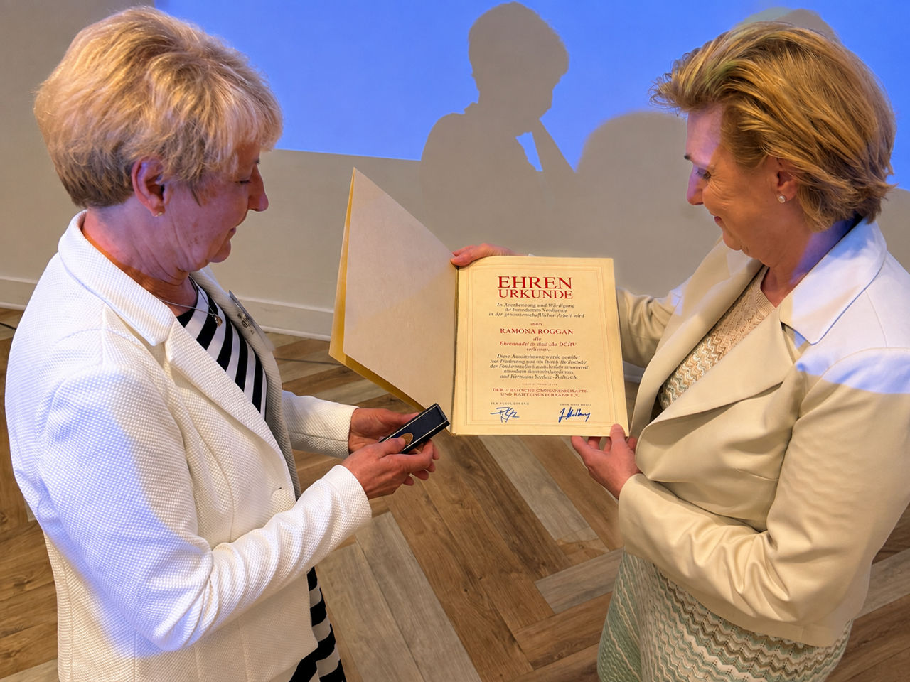 Frau Hella Lehmann vom Prüfungsverband der Genossenschaftsbanken überreicht die Ehrenurkunde an Frau Roggan