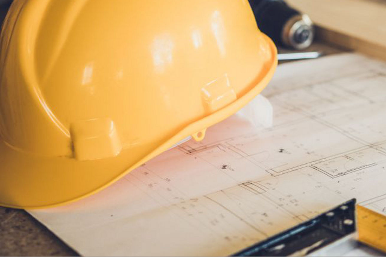 Bauhelm mit Bauplan und Werkzeug