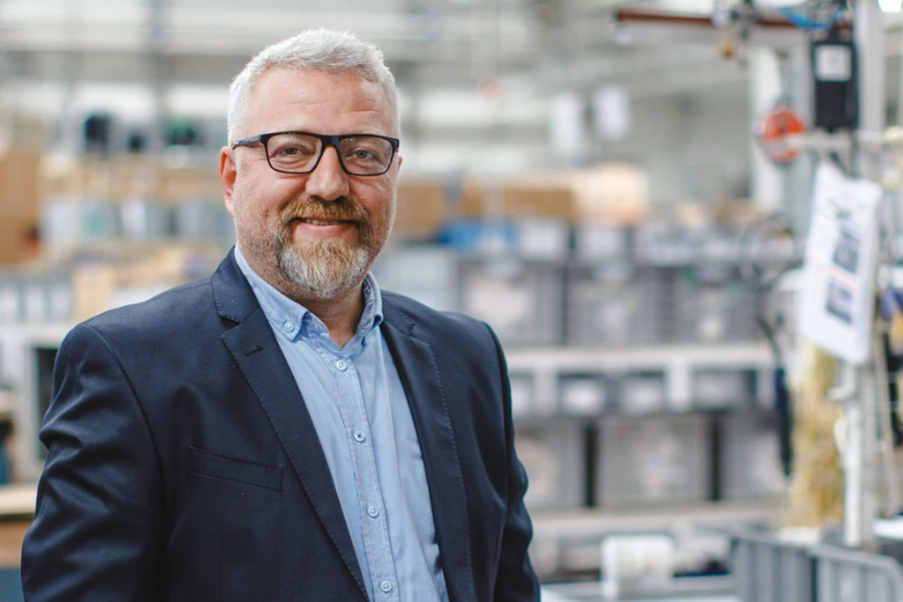 Unternehmer mit Brille und Jacket steht in einem Einkaufsmarkt