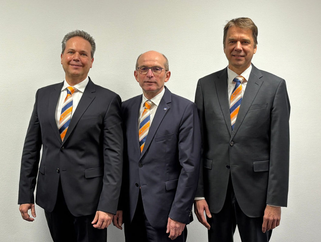  Drei Männer in formellen Anzügen und Krawatten stehen zusammen