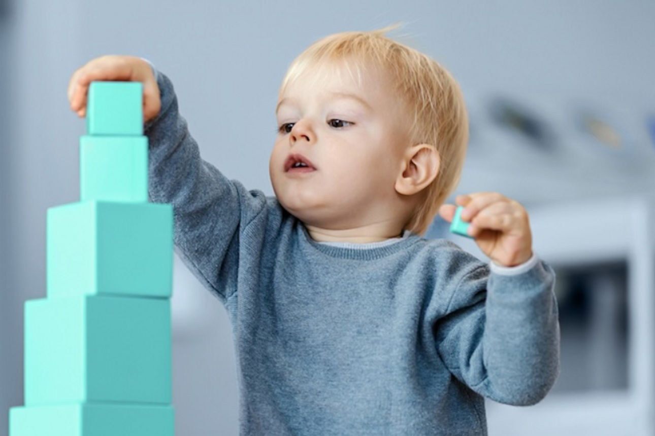 Ein Kind, das mit großen hellgrünen Bauklötzen spielt.