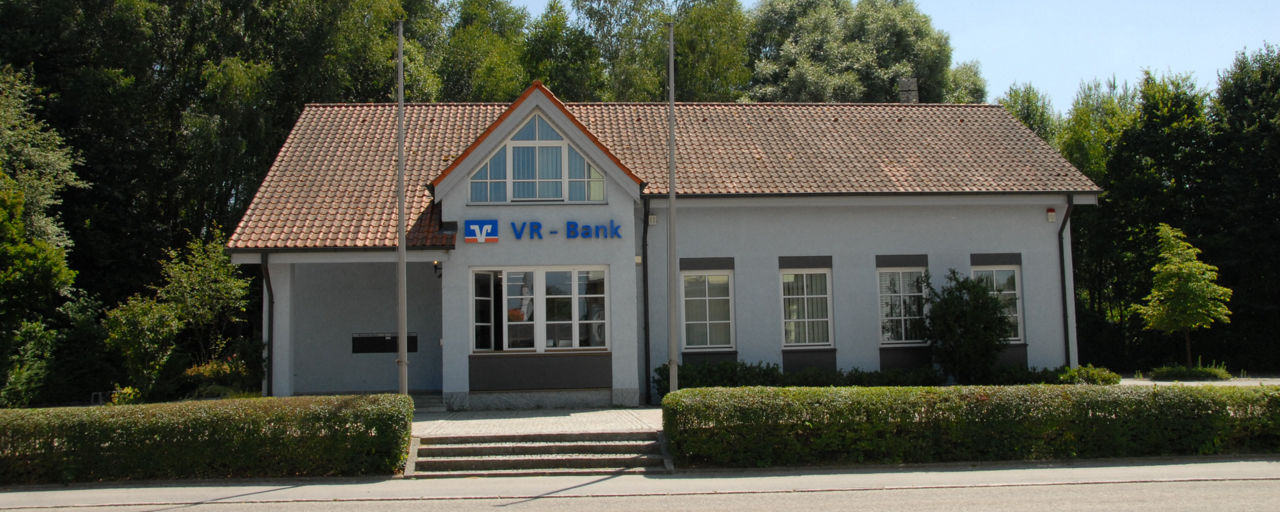 Unsere Geschäftstelle in Baierbach. Ein weißes Gebäude umgeben von Pflanzen.
