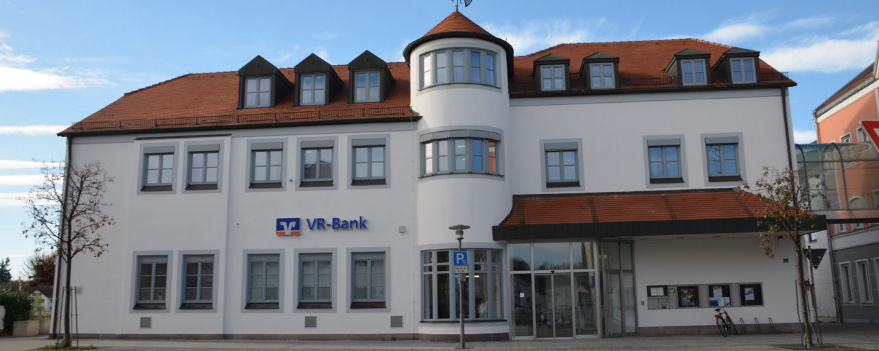 Unsere Geschäftstelle in Geisenhausen. Ein großes weißes Gebäude.