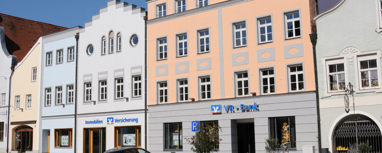Unsere Geschäftstelle in Vilsbiburg. Ein buntes Gebäude in der Mitte des Stadtplatzes Vilsbiburg.