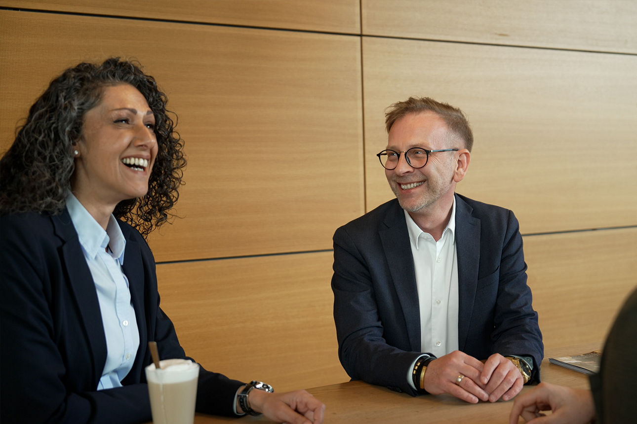 Eine Frau und ein Mann sitzen nebeneinander und trinken gemeinsam einen Kaffee