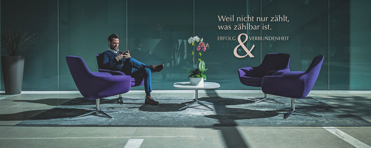 Mann in Sitzgruppe schaut aufs Handy
