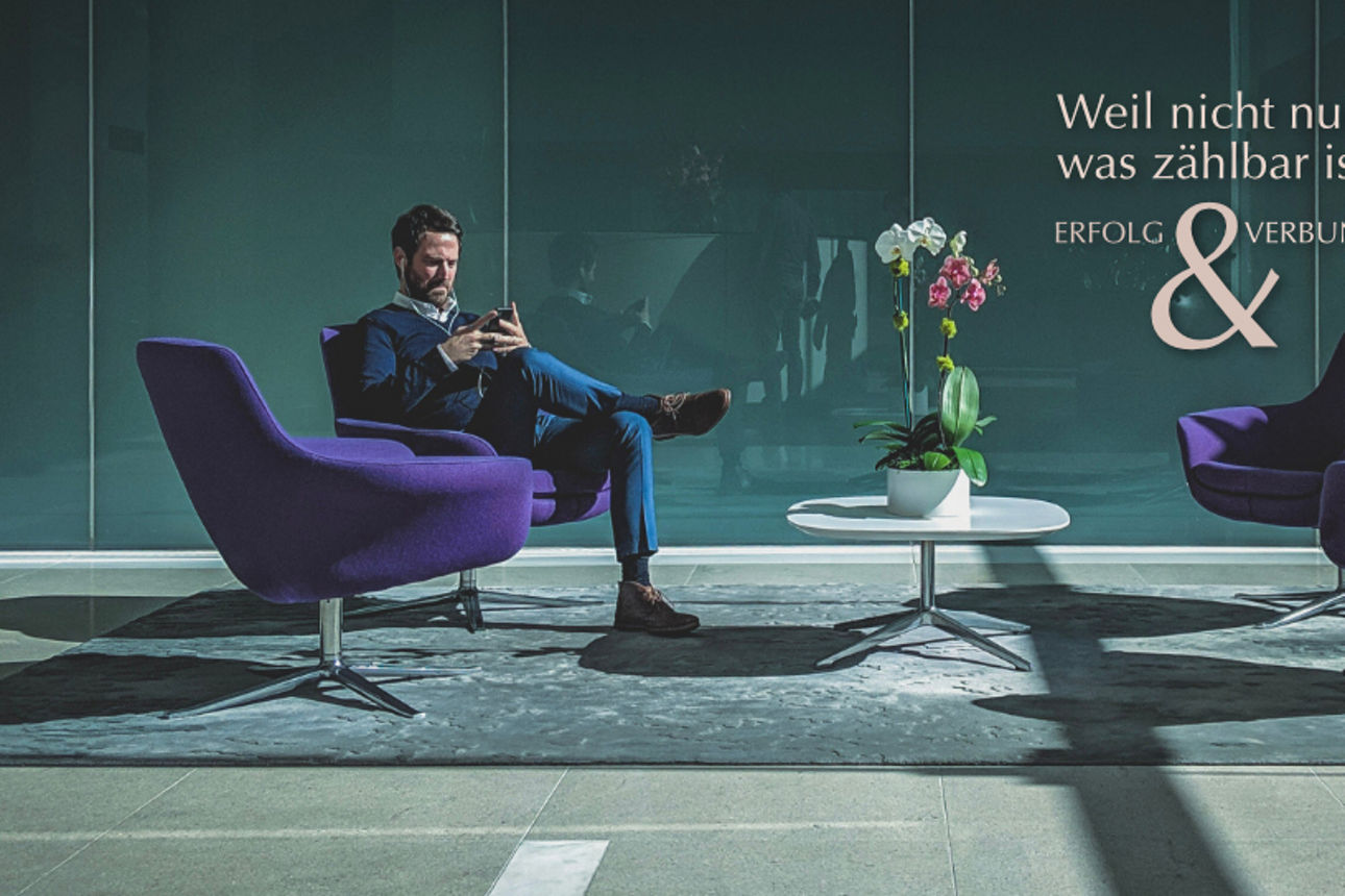 Mann in Sitzgruppe schaut aufs Handy