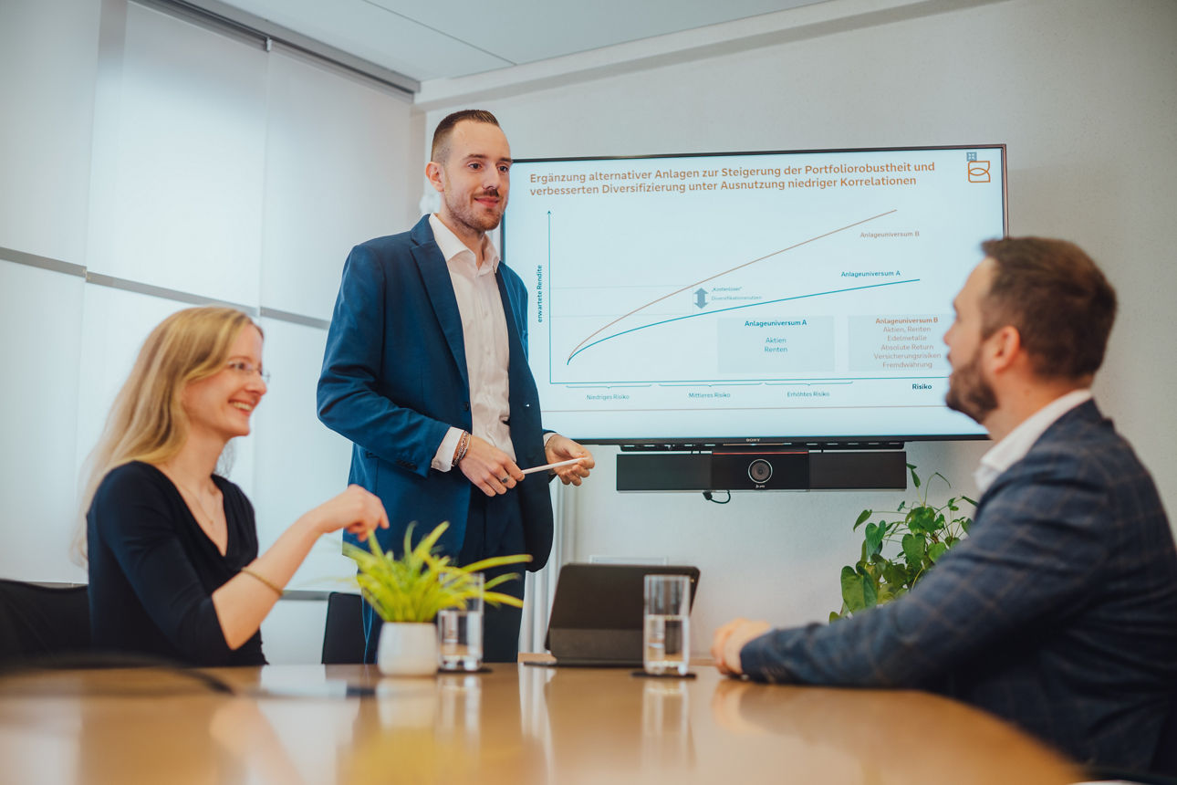 Drei Personen schauen auf einen Bildschirm und besprechen etwas