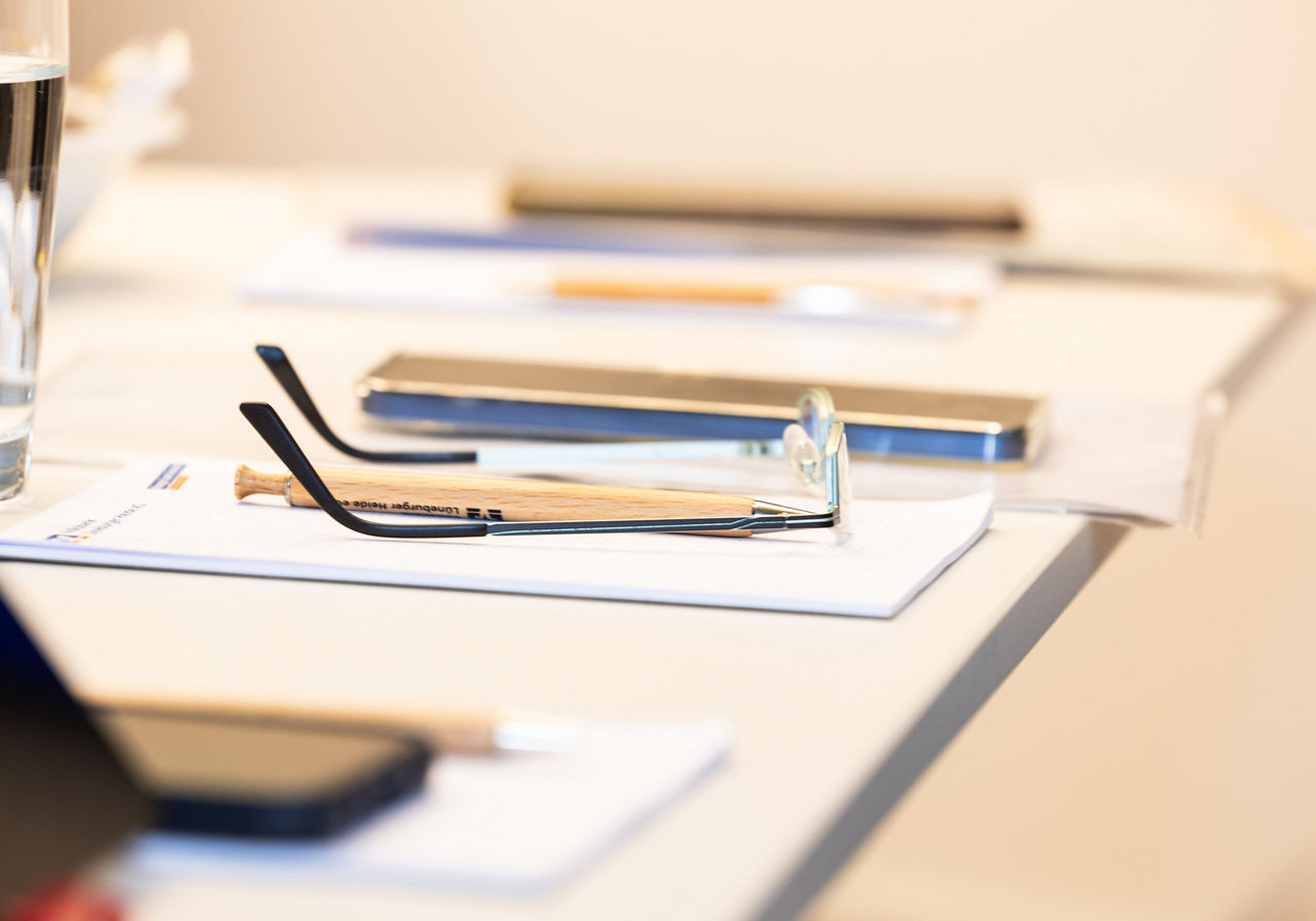 Schreibtisch mit Brille, Papier und Stiften