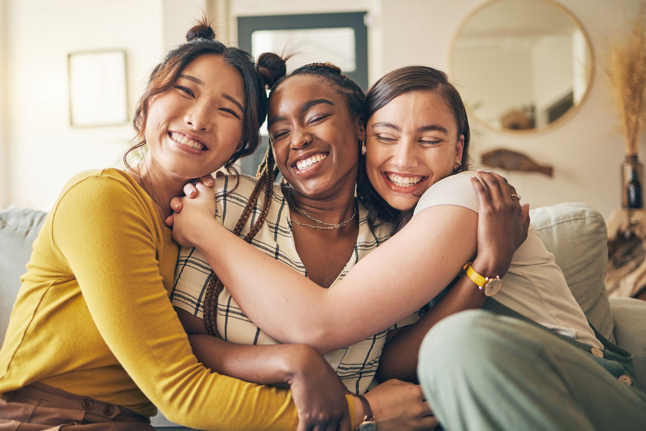 Cheerful young friends in a cuddle on the couch