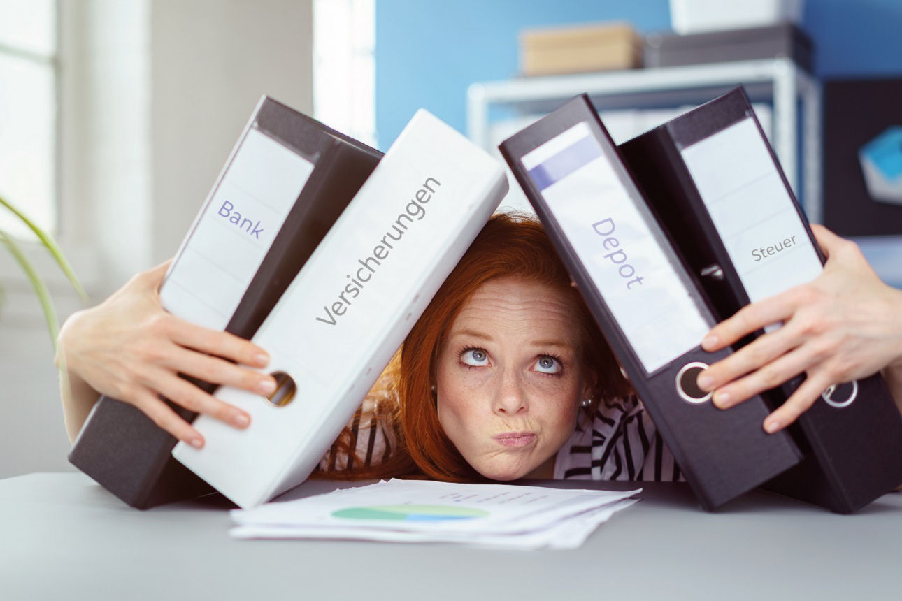 junge überfordere Frau lehnend auf dem Tisch, wird von Aktenordnern umringt