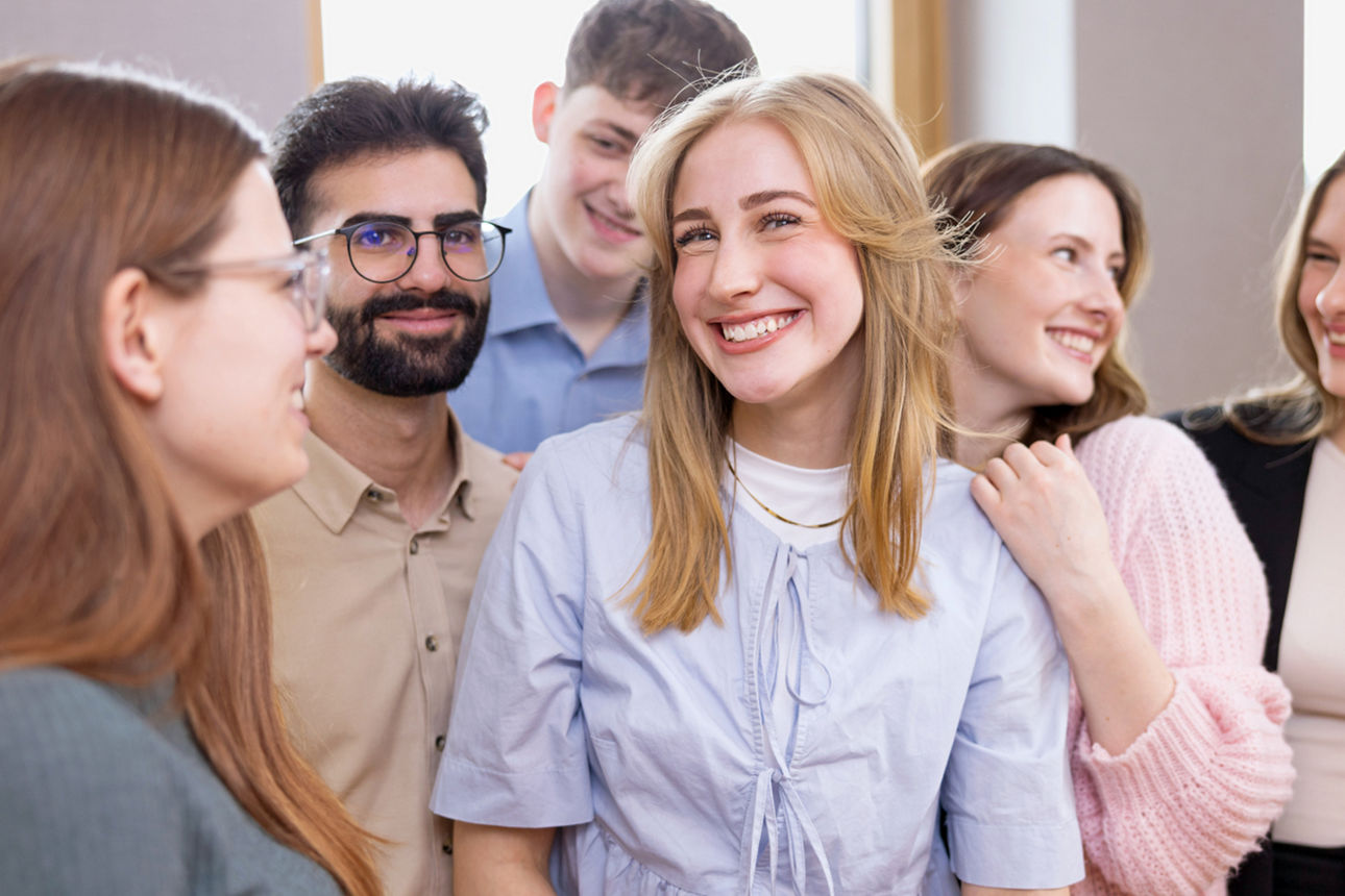 Sechs Auszubildende lachen sich gegenseitig freudig an.