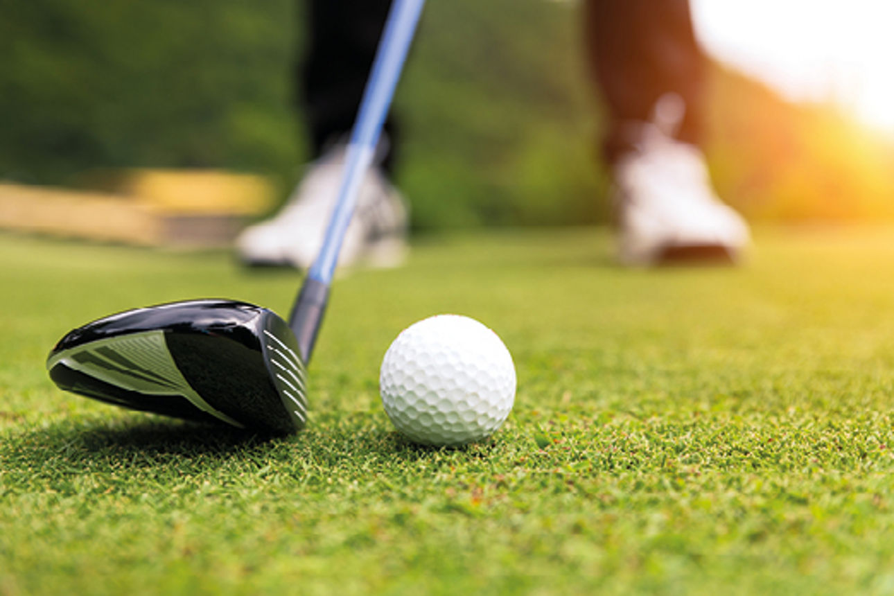 Mann mit Golfschläger und Golfball auf dem Golfplatz