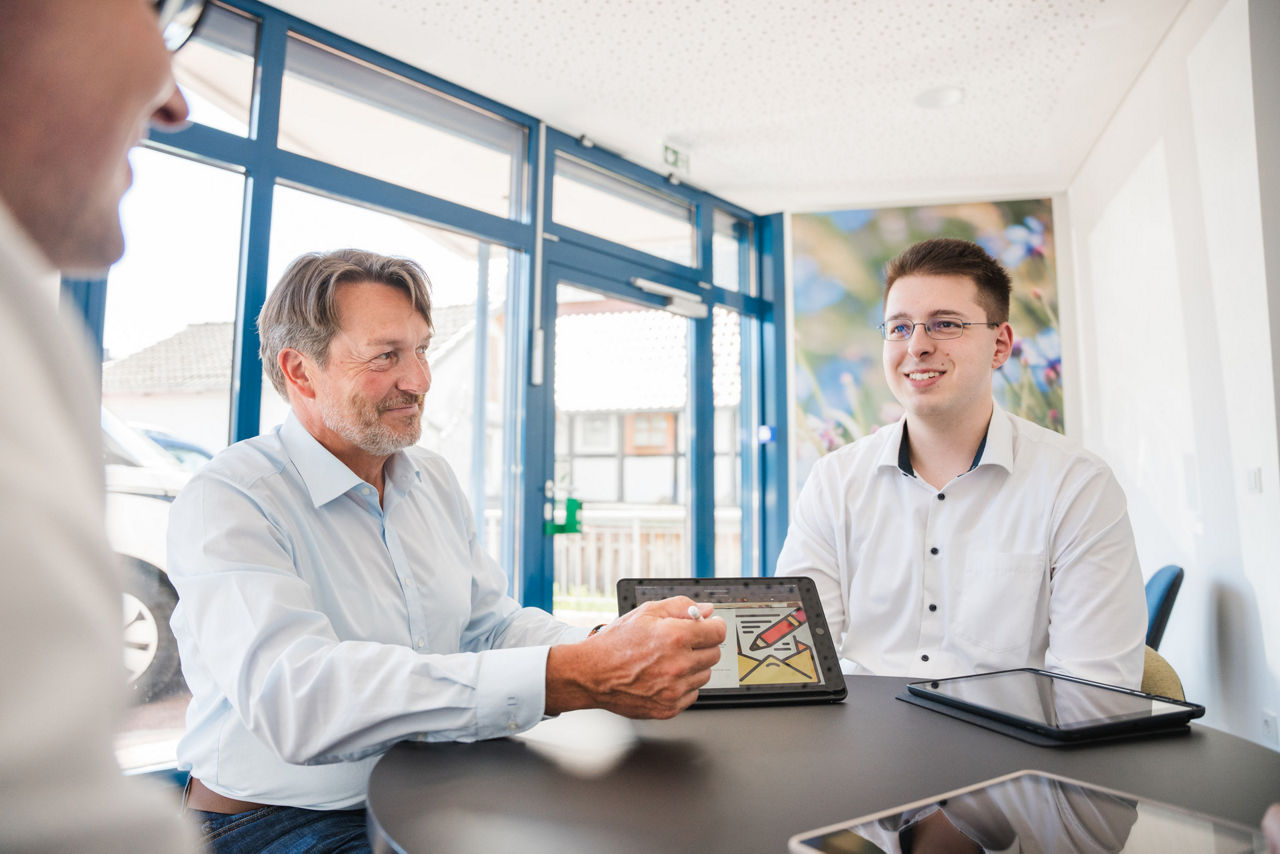 Zwei junge Kollegen besprechen sich mit einem erfahrenen Kollegen