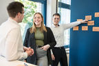 Die Azubis der VBBS stehen an einer Flipchart und hängen Post Its auf