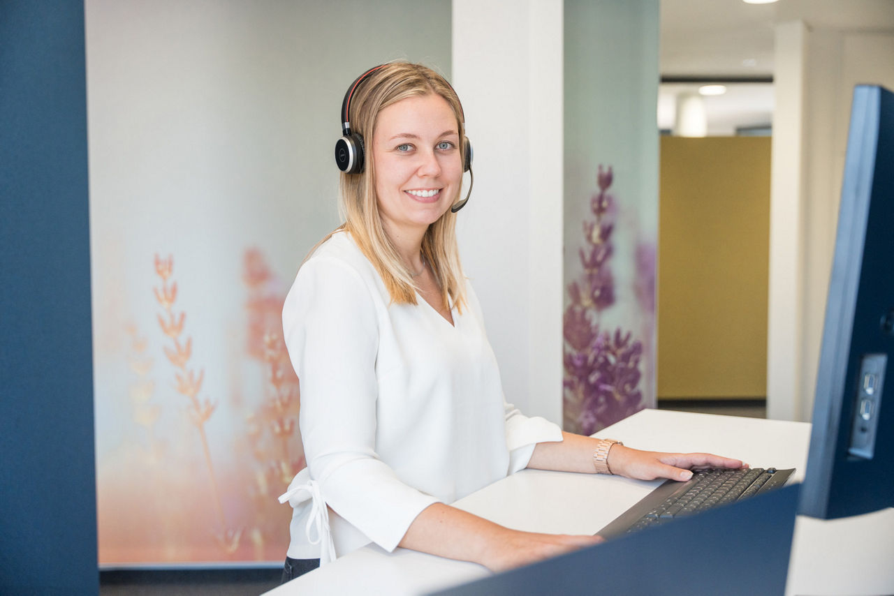 Eine Frau, die in einem modernen Büro steht und ein Headset trägt