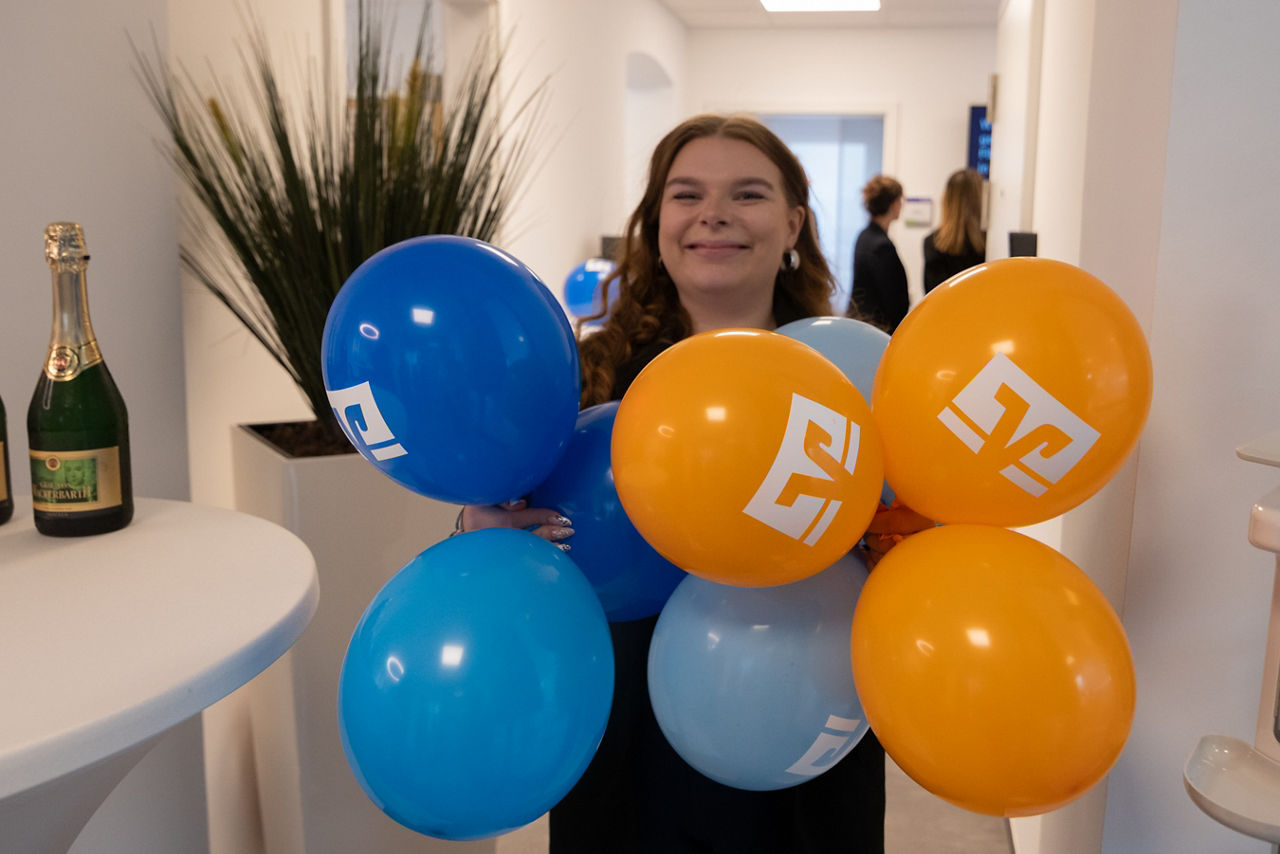 Eine Frau trägt Luftballons in blauer und oranger Farbe mit dem Volksbanklogo
