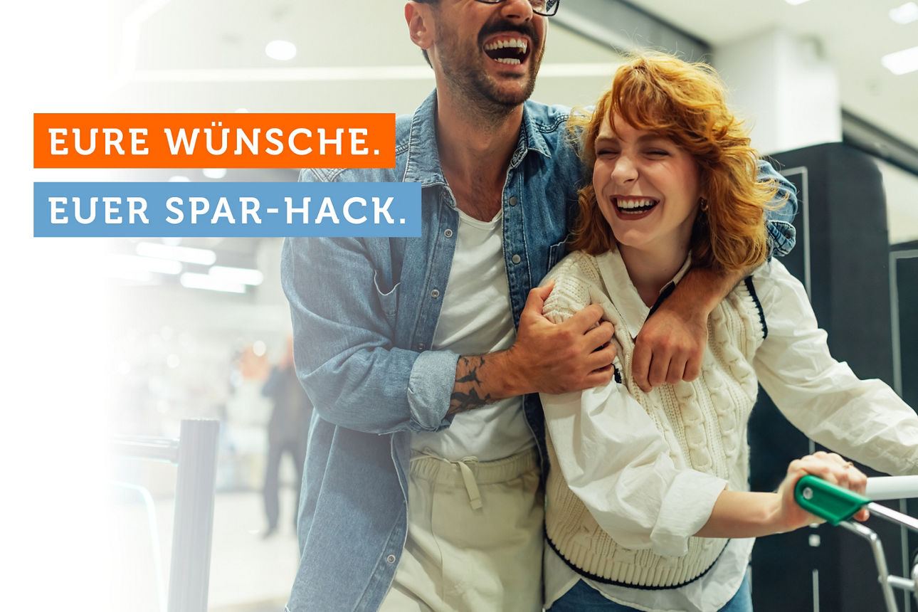 Ein junges Pärchen schiebt einen Einkaufswagen im Supermarkt.