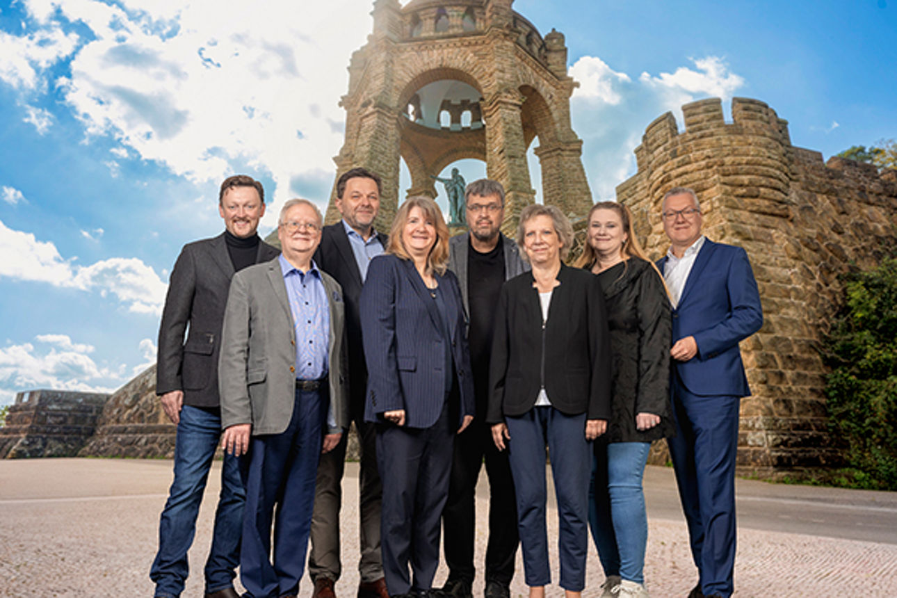 Eine siebenköpfige Gruppe steht vor dem Kaiser-Wilhelm-Denkmal in Porta Westfalica