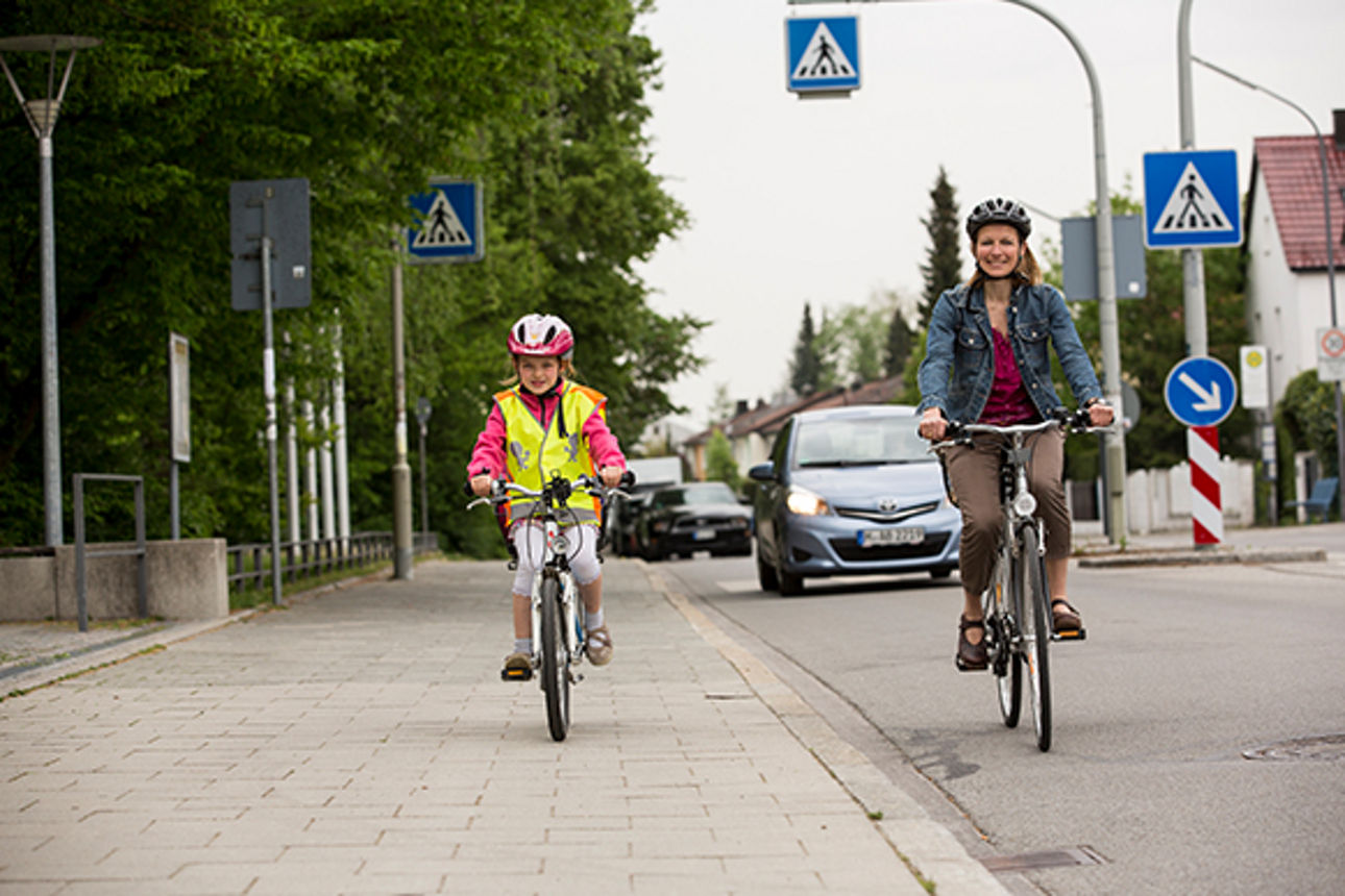 Mutter und Tochter üben per Fahrrad auf Straße und Gehweg den Schulweg