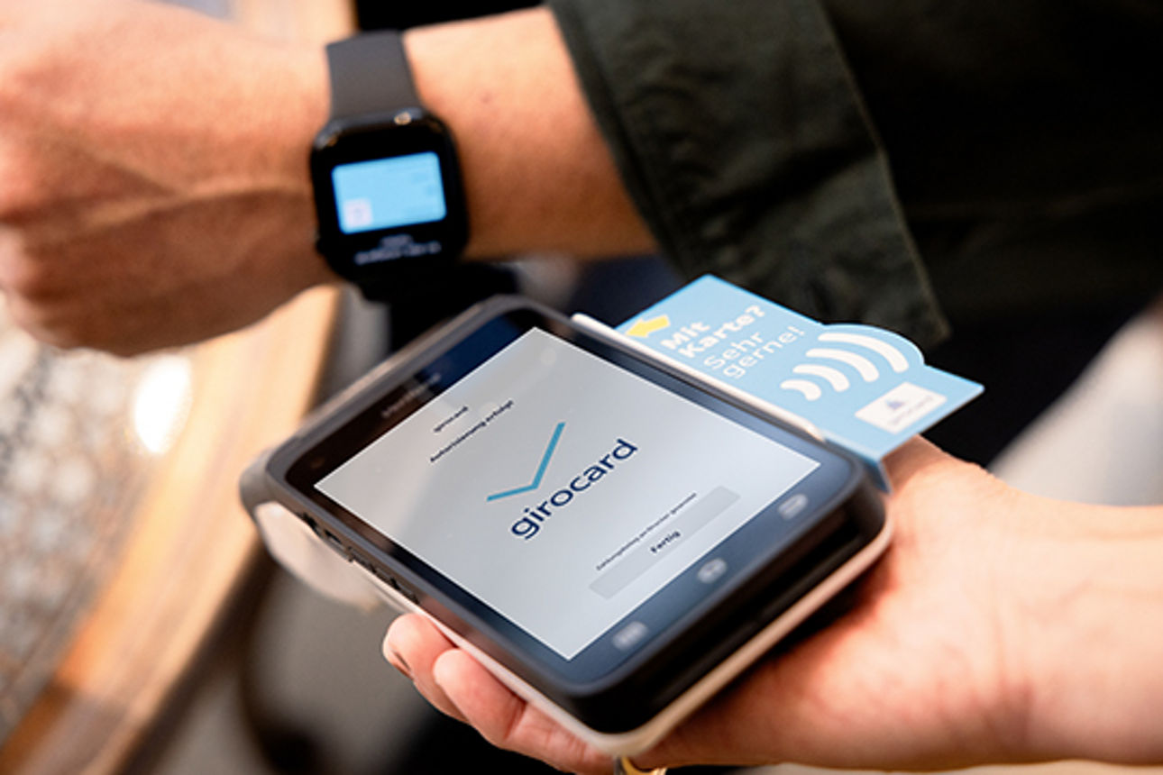 Mit einer Smartwatch am Handgelenk wird an einem Terminal kontaktlos bezahlt