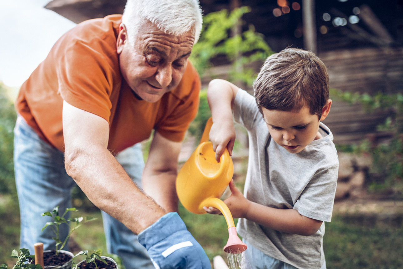 Opa und Enkel arbeiten glücklich in ihrem Garten.