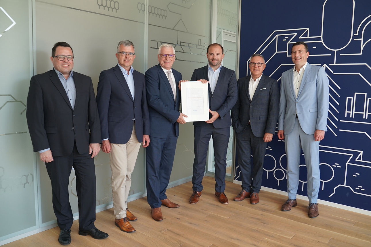 Männer, darunter Mitarbeiter der Volksbank Mittlerer Neckar eG stehen in einer Reihe und halten eine Urkunde