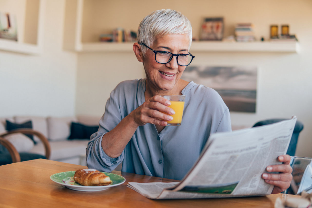 Eine Frau sitzt am Tisch und liest eine Zeitung