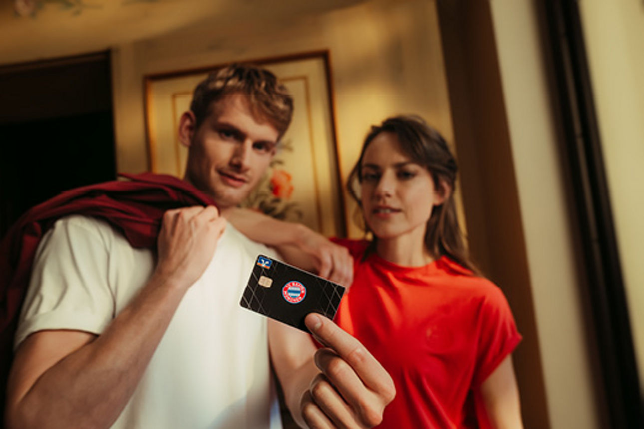 Eine Frau und ein Mann schauen auf die Kreditkarte im exklusiven FC Bayern Sonderdesign