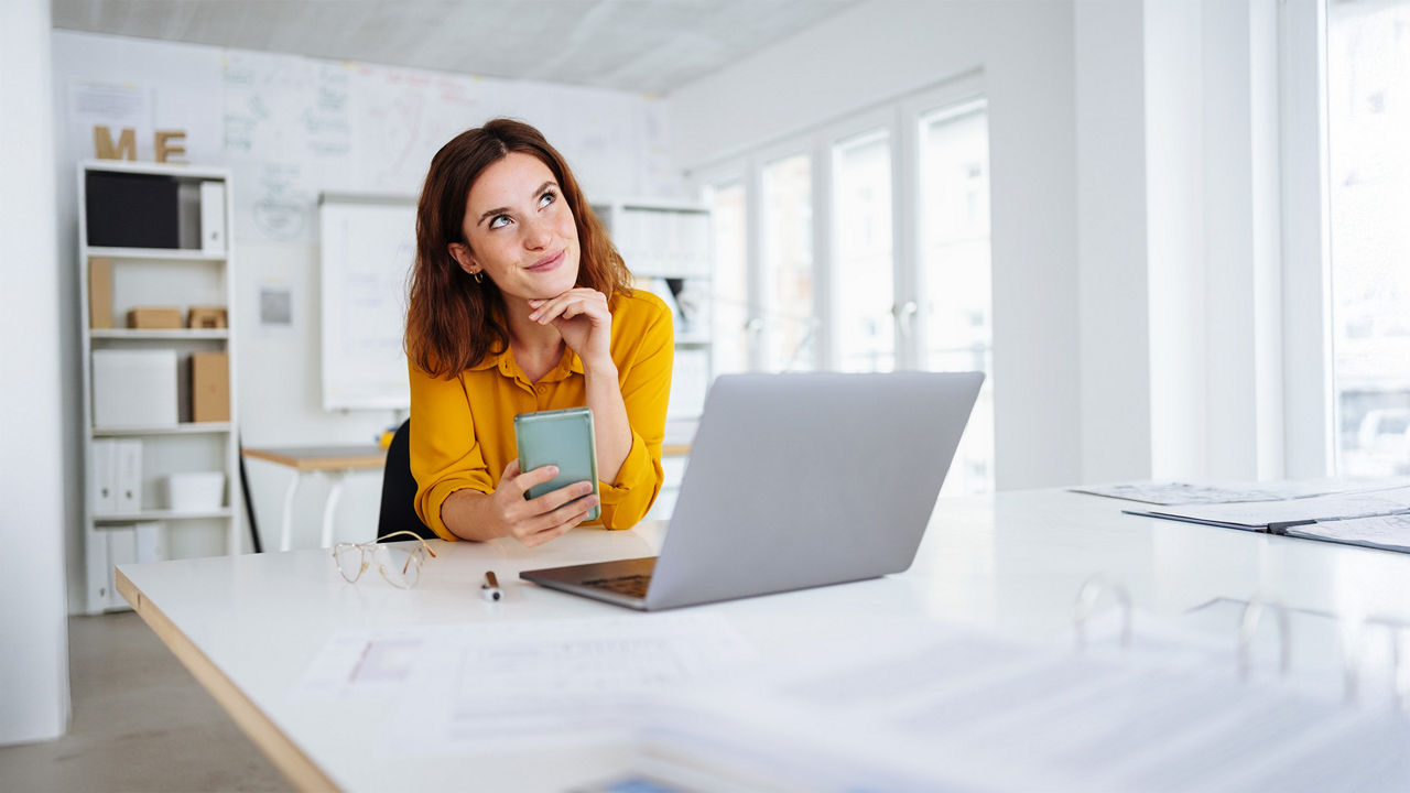 Eine Frau sitzt überlegend vor ihrem Laptop
