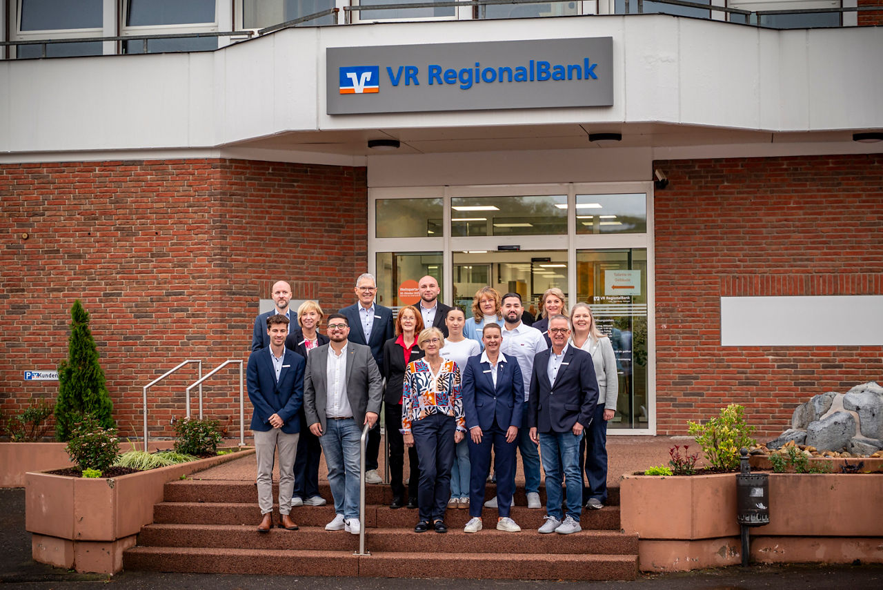 Das Bild zeigt das Team der VR RegionalBank Birstein vor der wiedereröffneten Filiale