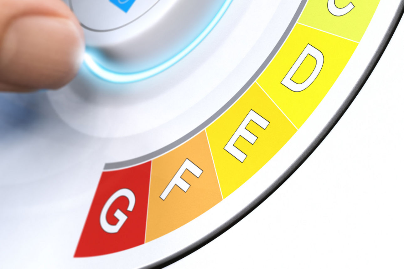 Hand dreht an Knopf mit Energieeffizienten Eingruppierungen A bis G