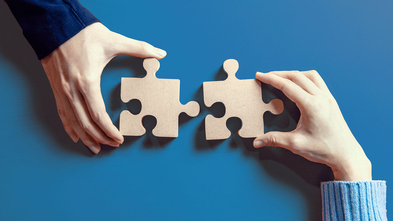 2 Hände führen 2 Puzzleteile zueinander