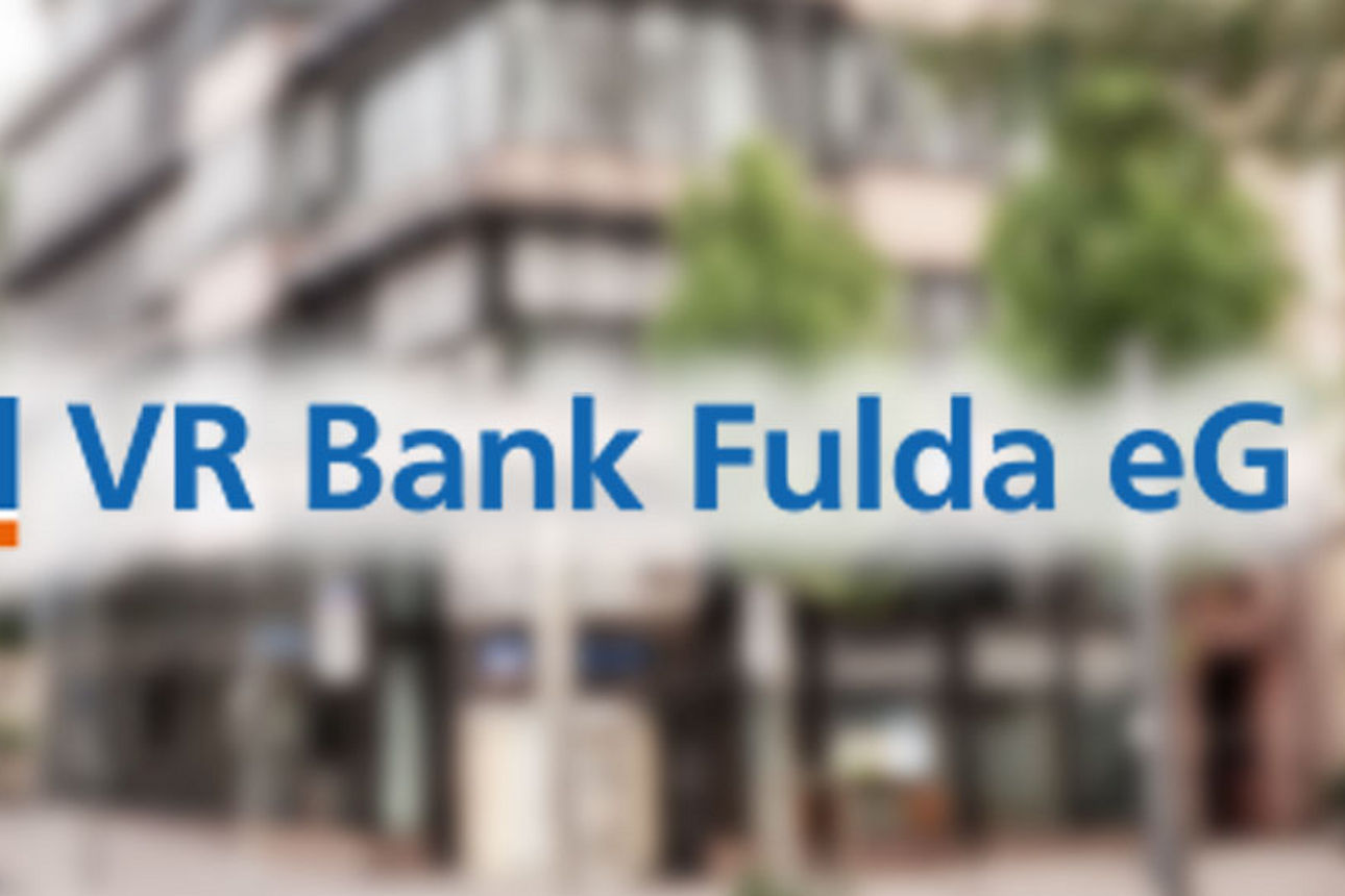 Im Hintergrund unscharf das Gebäude der ehemaligen VR Bank Fulda in Fulda, im Vordergrund das Logo