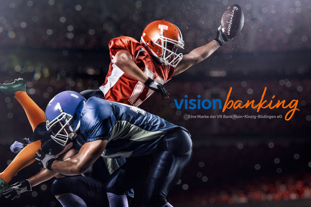 Das Bild zeigt zwei Footballspieler, wobei einer im Sprung ist und einen Football fängt.  auf der rechten Bildseite ist das VisionBanking Logo zu sehen, darunter der Claim Eine Marke der VR Bank Main-Kinzig-Büdingen eG