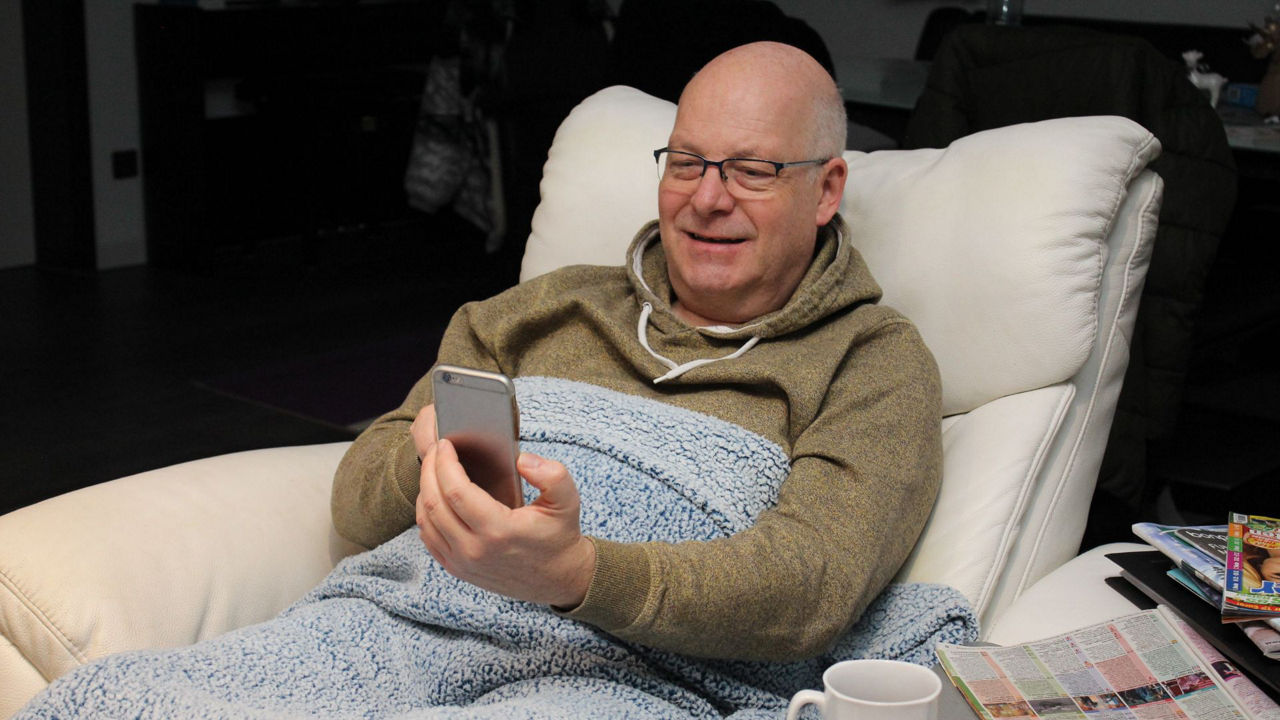 Mann liegt auf Sofa und schaut in sein Smartphone