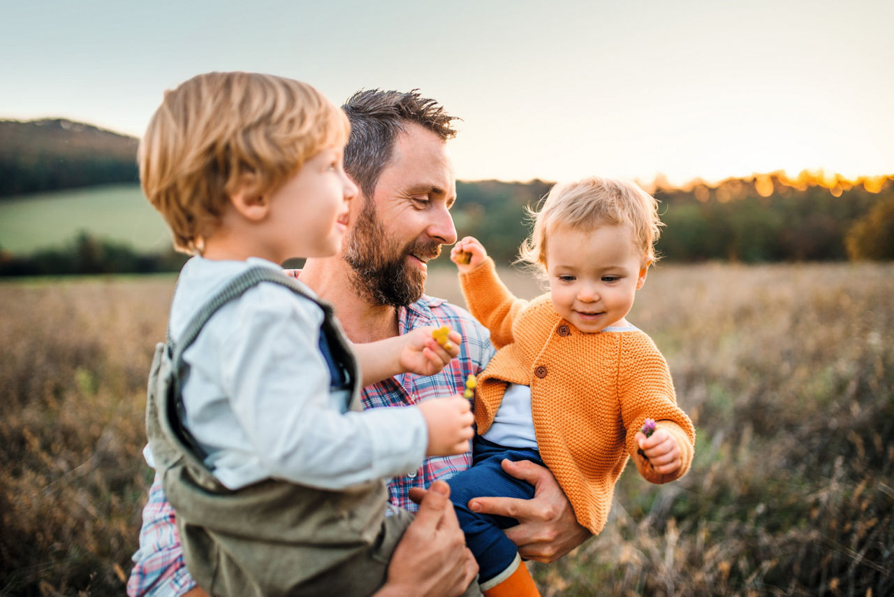 Familienvater mit zwei Kindern auf dem Arm