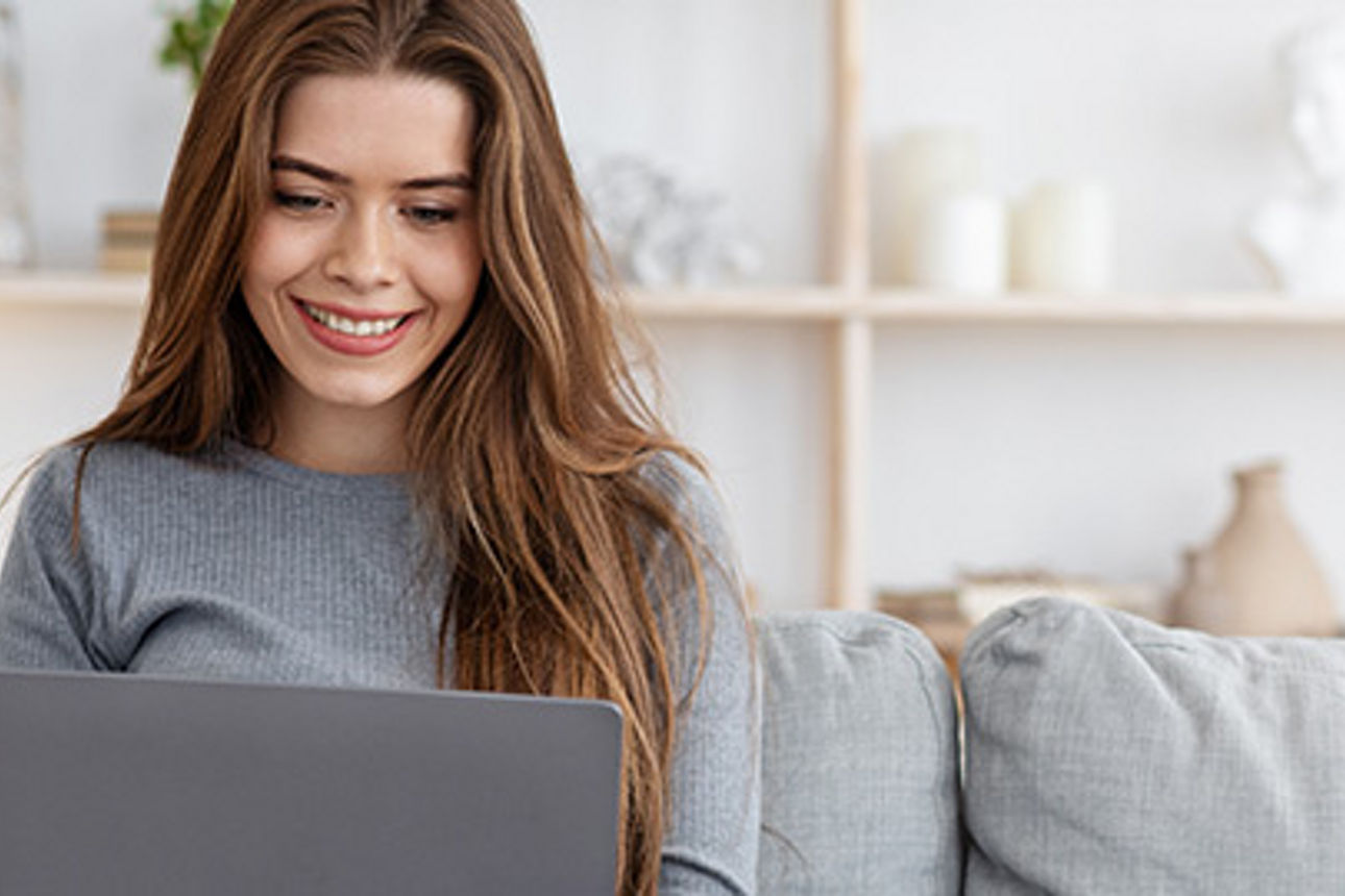 Frau sitzt mit Laptop auf dem Sofa