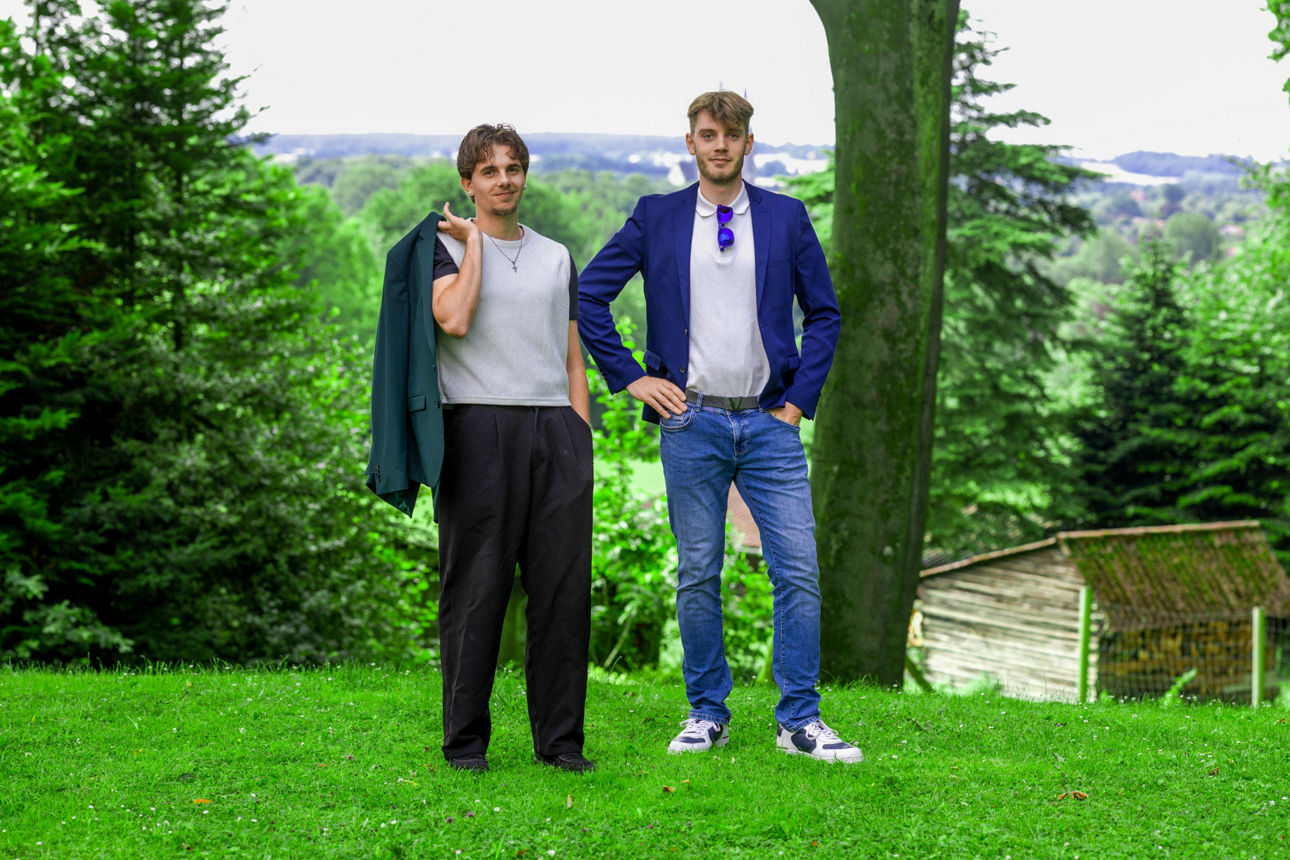 Zwei junge Männer in Businesskleidung stehen auf einer Wiese