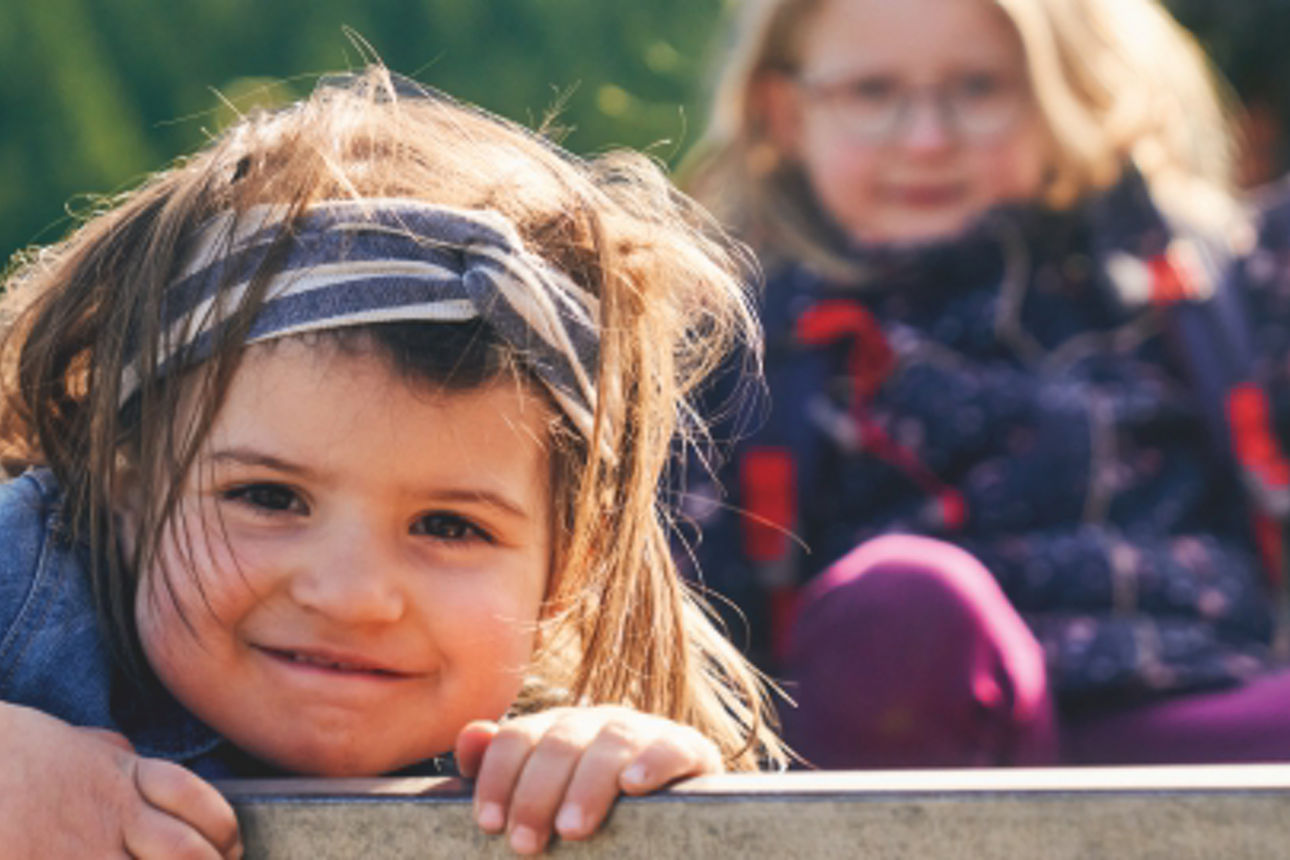 Zwei Kinder sitzen in deinem Traktoranhänger.