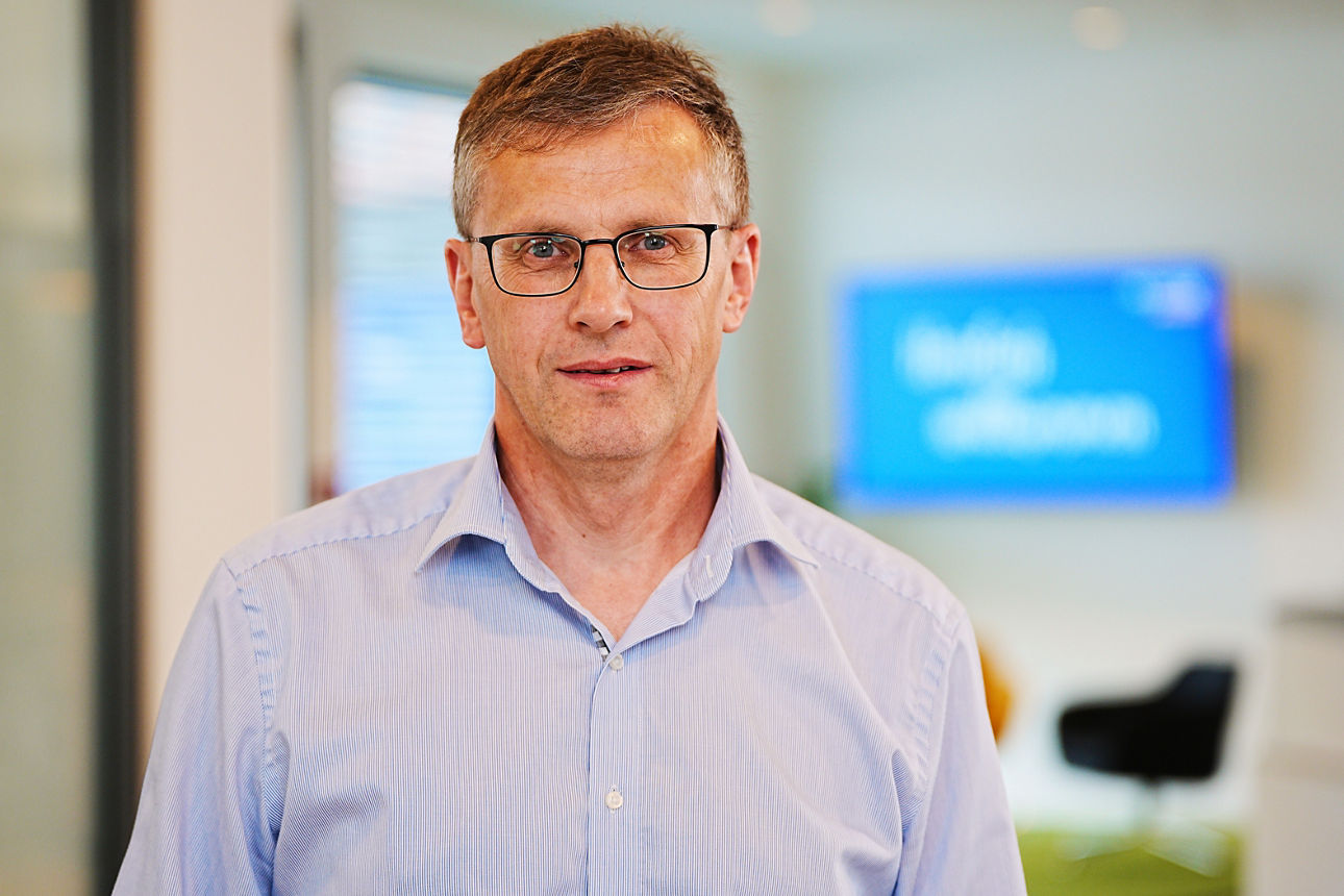 Ein Herr mit einem blauen Hemd und einer Brille in den Geschäftsräumen der Bank.
