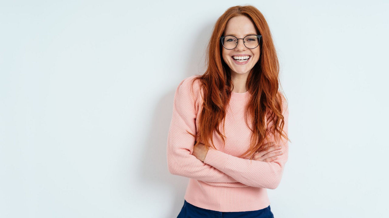 Eine junge hübsche Dame mit verschränkten Armen schaut in die Kamera