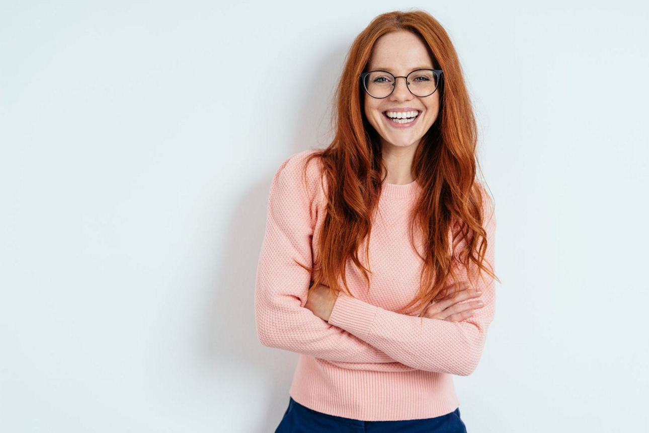 Eine junge hübsche Dame mit verschränkten Armen schaut in die Kamera